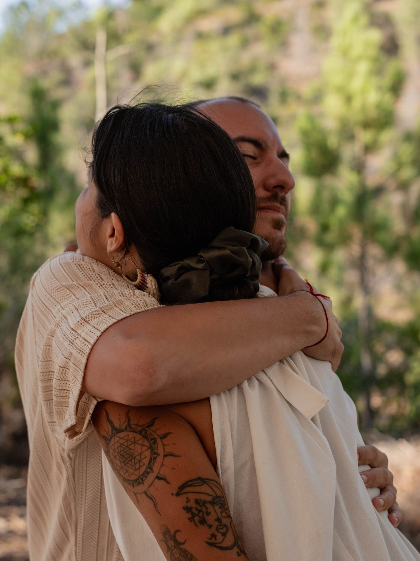 Two people sharing a warm embrace outdoors in golden light