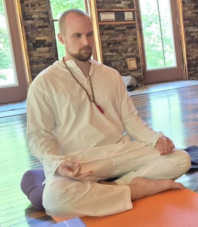 Mitchell meditating cross-legged in a sunlit studio